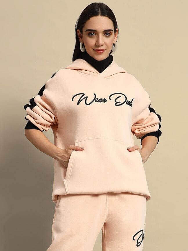Woman wearing a beige-black fleece hoodie with 'Wear Dude' text, showcasing a stylish and comfortable fashion choice.