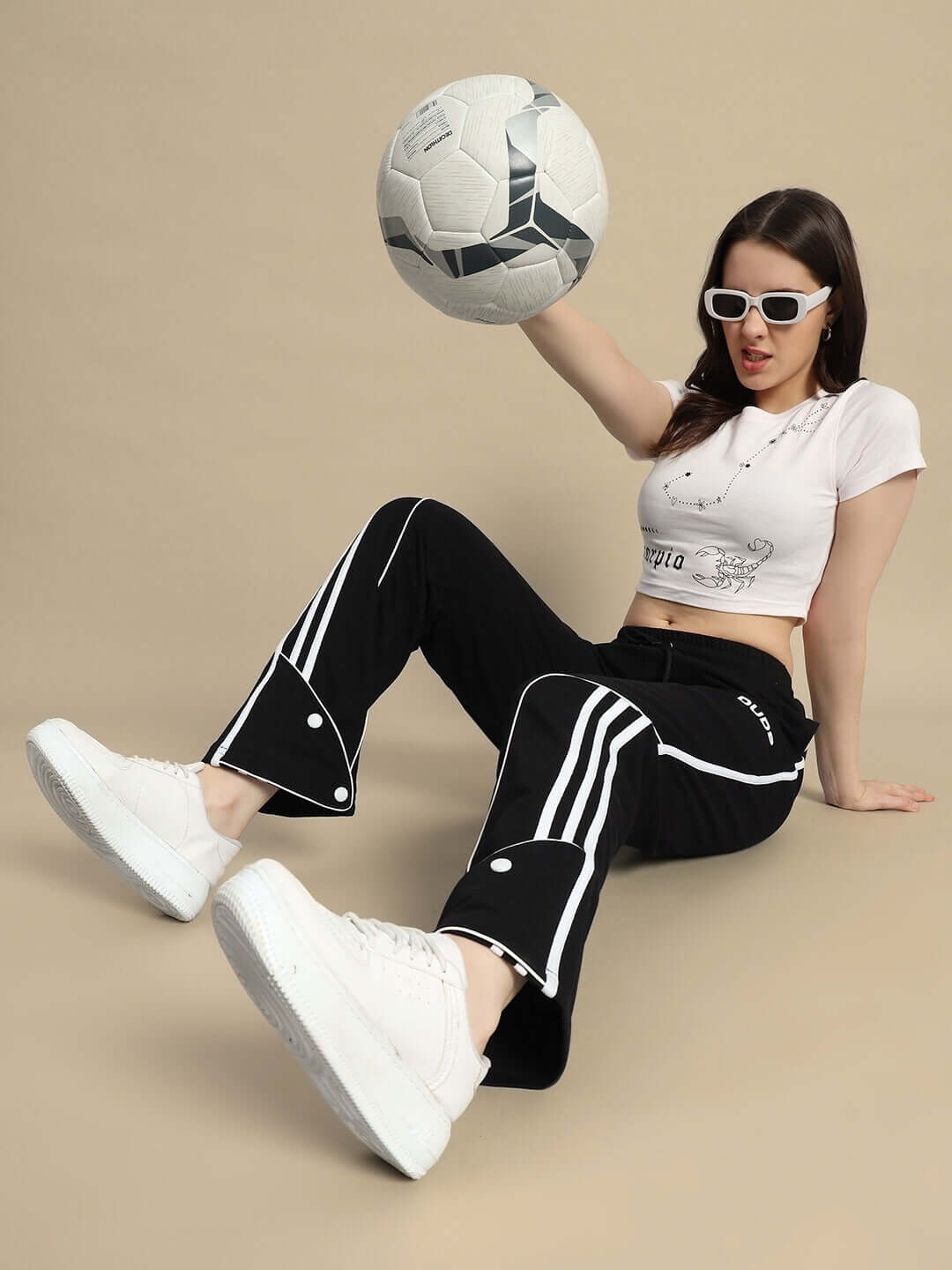 Woman wearing DUDS black ripple contrast joggers playing with a soccer ball, showcasing sporty style and flexibility.
