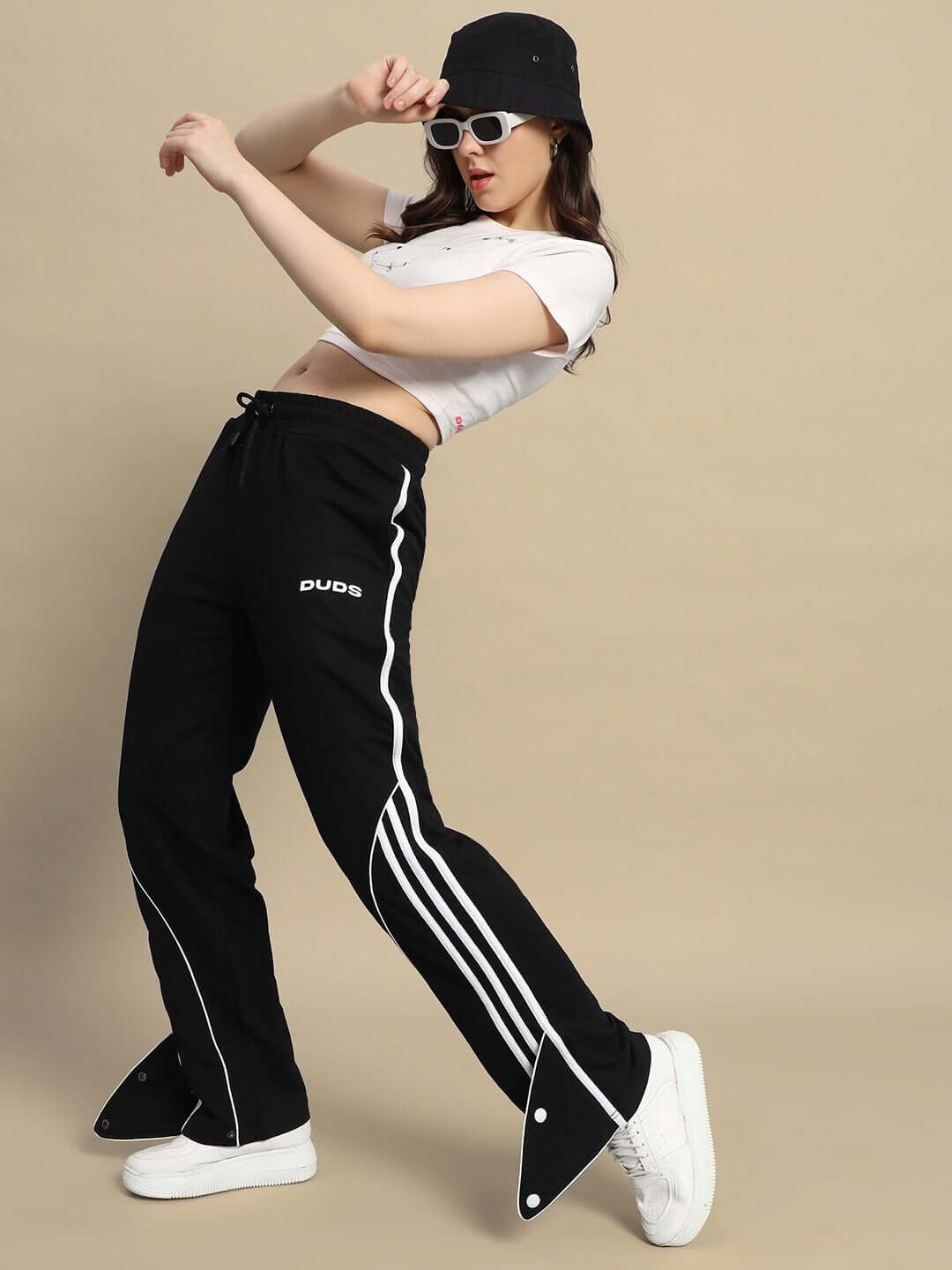 Woman wearing DUDS Women's Ripple Contrast Joggers in black with stripe detail, paired with a crop top and sunglasses.