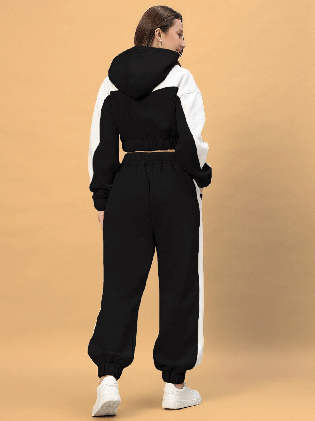 Back view of a model wearing the WOMEN'S RIZZLER COLORBLOCK CO-ORD in black with white accents, showcasing a stylish hooded top and pants.