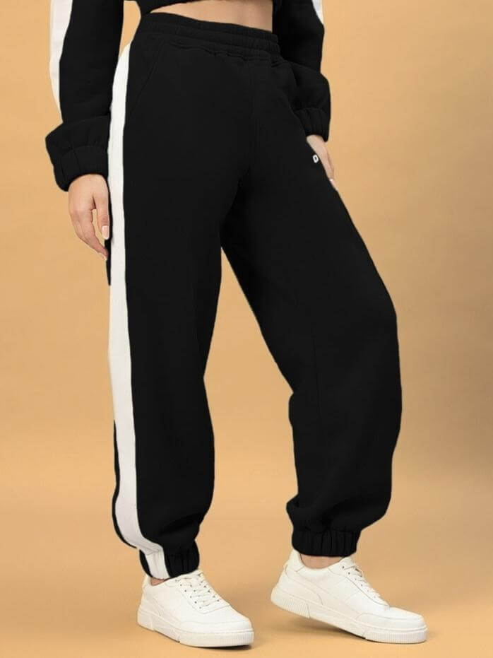 WOMEN RIZZLER FLEECE COLORBLOCK JOGGER BLACK featuring bold side stripes, shown styled with white sneakers for a modern look.
