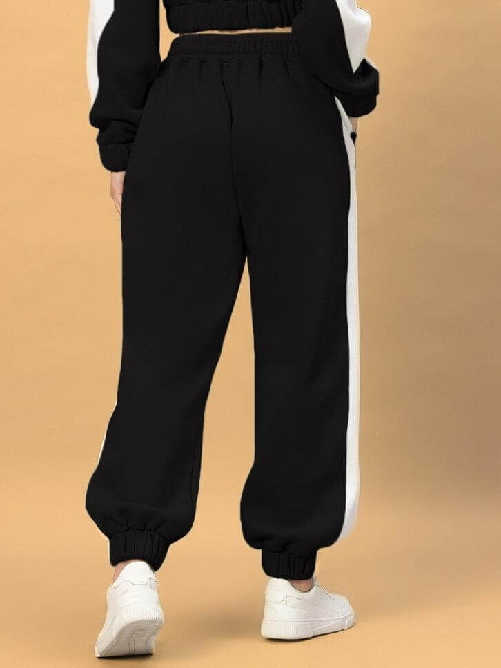 Back view of WOMEN RIZZLER FLEECE COLORBLOCK JOGGER BLACK with white stripes, showcasing a relaxed fit for stylish comfort.