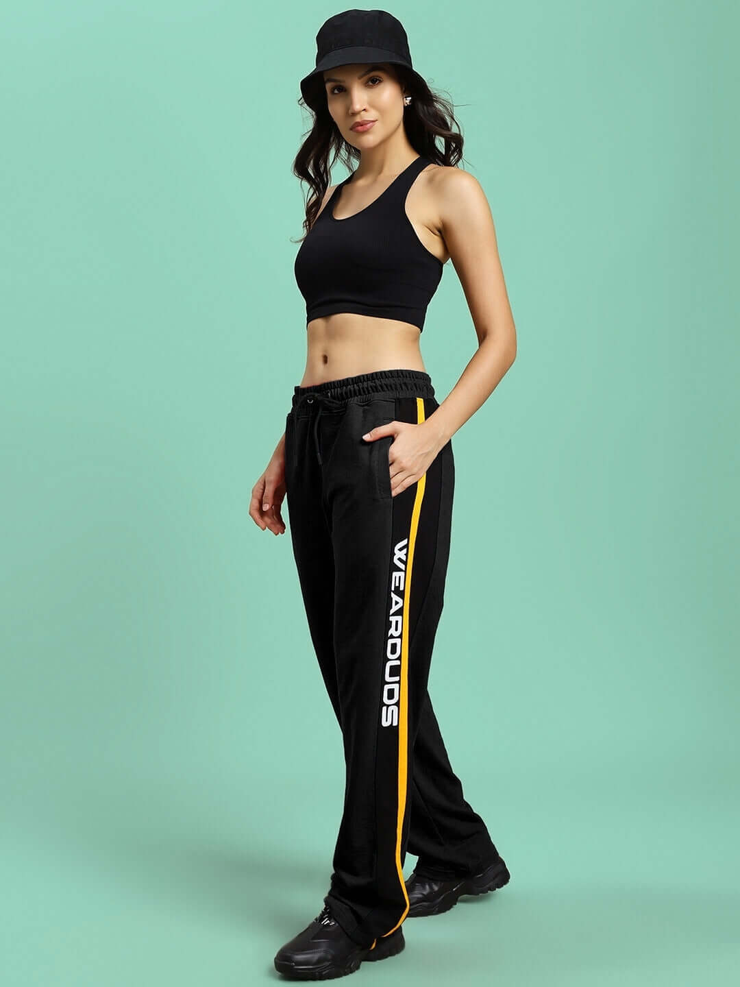 Model wearing black Women's Roger Relaxed-Fit Joggers with yellow stripe, from DUDS, showcasing comfortable casual wear.