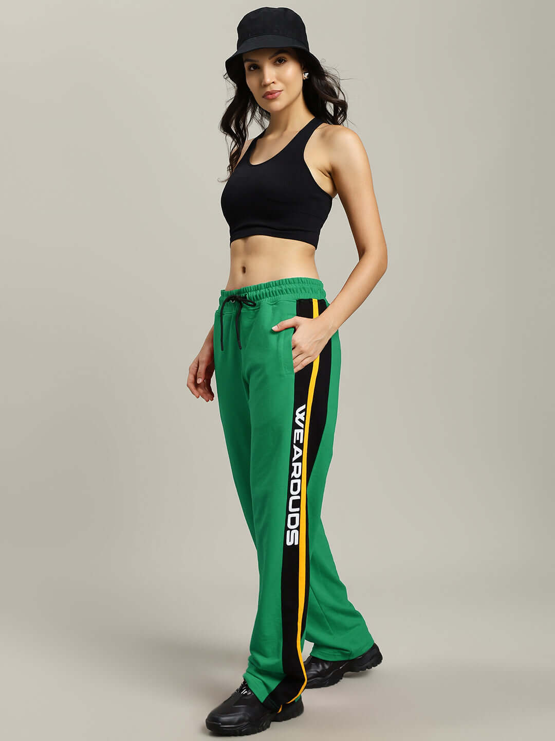 Model wearing green relaxed-fit joggers with custom fit option, black tank top, and hat, designed by DUDS tailors.