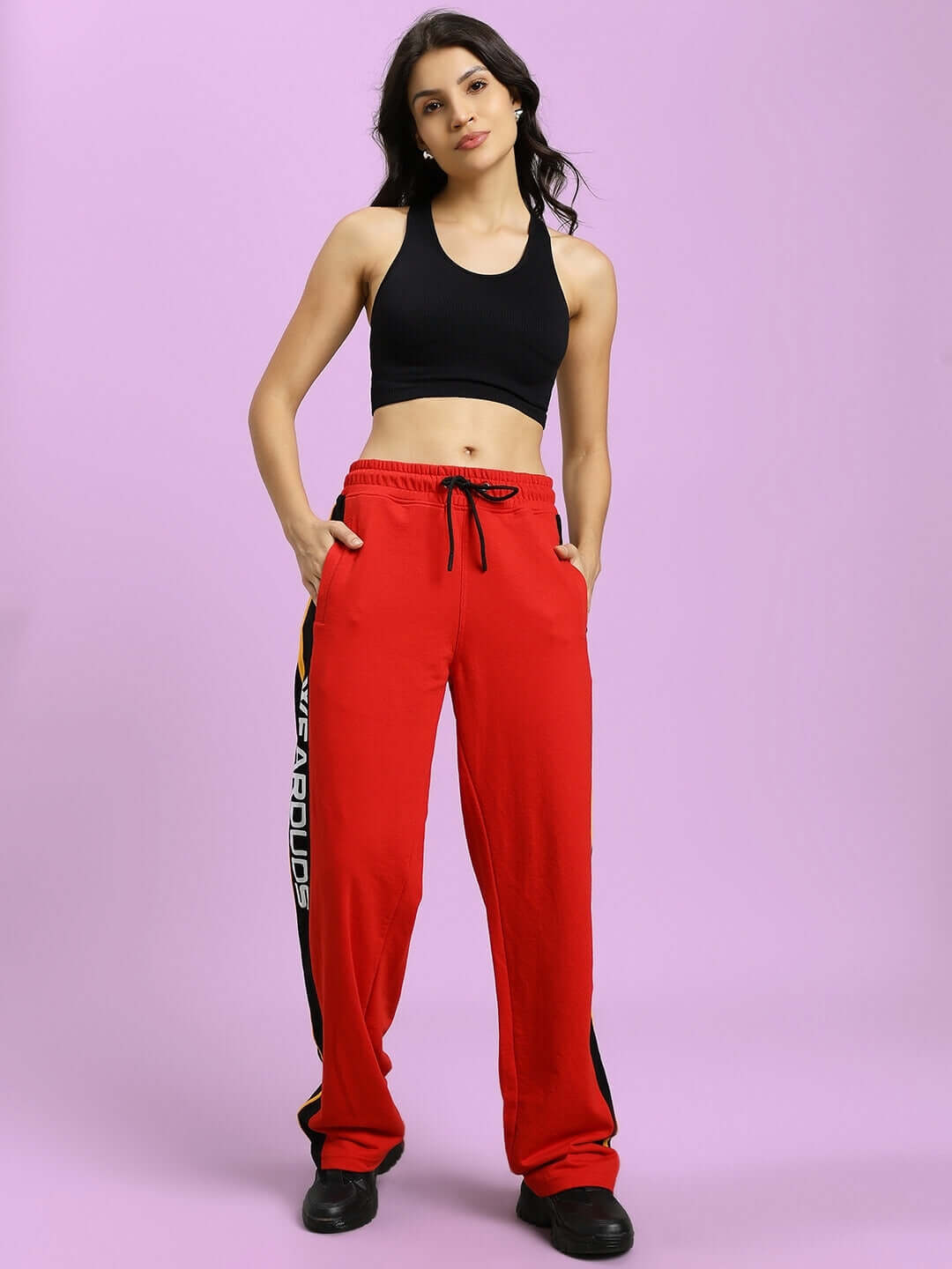 Model in WOMEN'S ROGER RELAXED-FIT JOGGERS RED with black top, showcasing stylish and comfortable fit, front view against pink background.