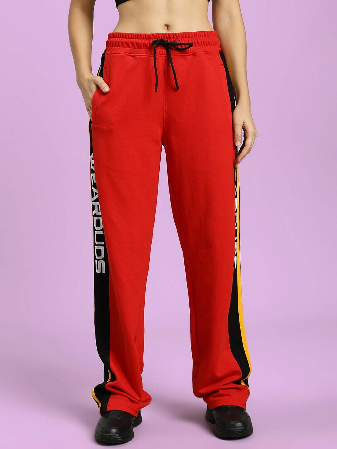 Model wearing WOMEN'S ROGER RELAXED-FIT JOGGERS RED with black and yellow side stripes