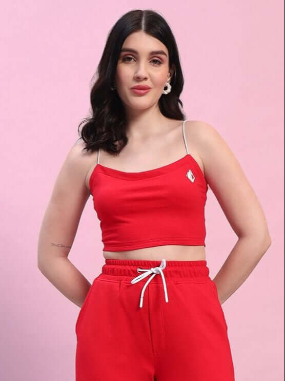 Woman wearing red Rosella crop-top, made from premium heavy gauge cotton fabric. Features spaghetti straps, against pink background.