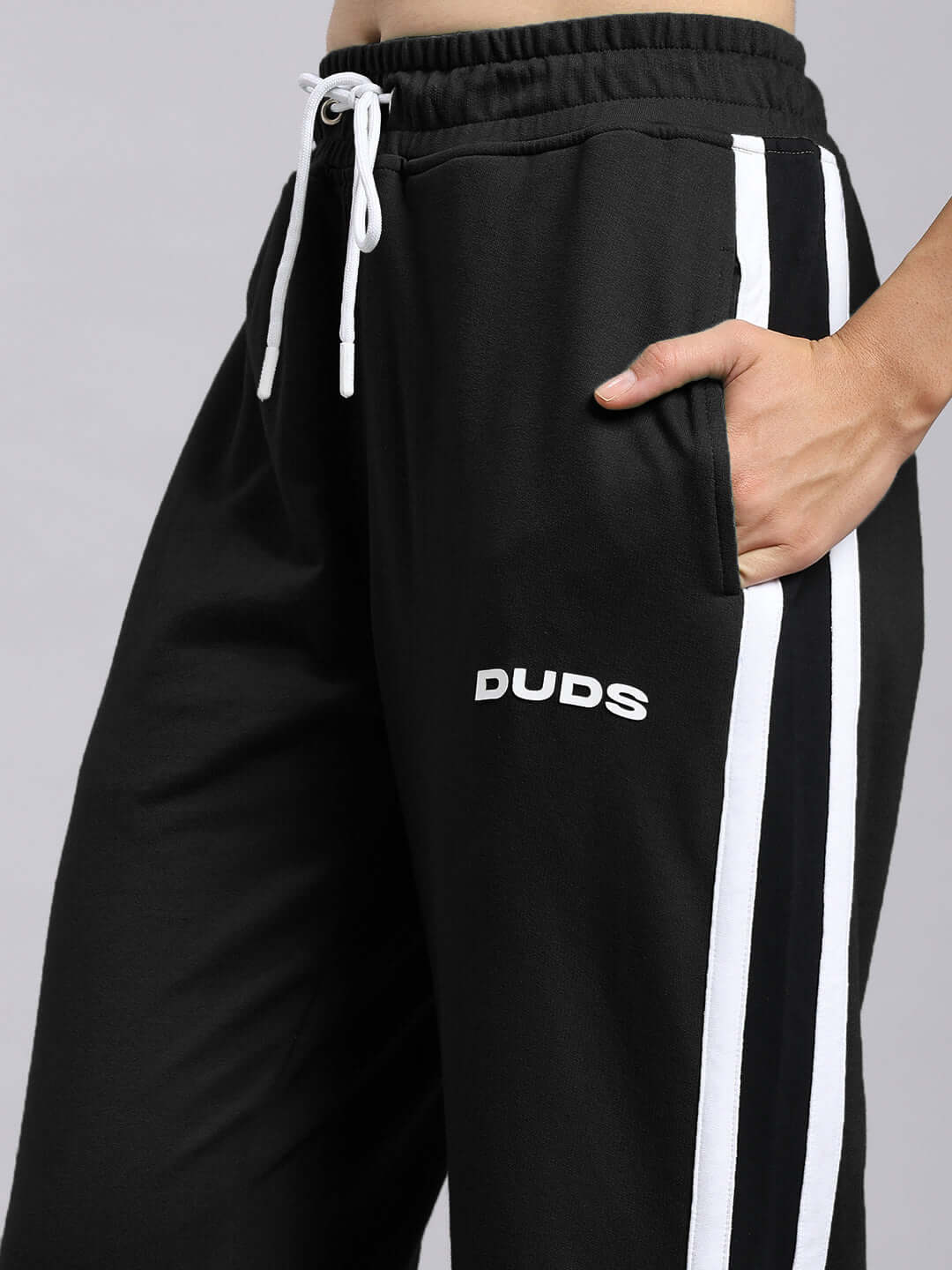 Close-up of women's black DUDS joggers, featuring white side stripes and relaxed fit design, perfect for custom or relaxed wear.