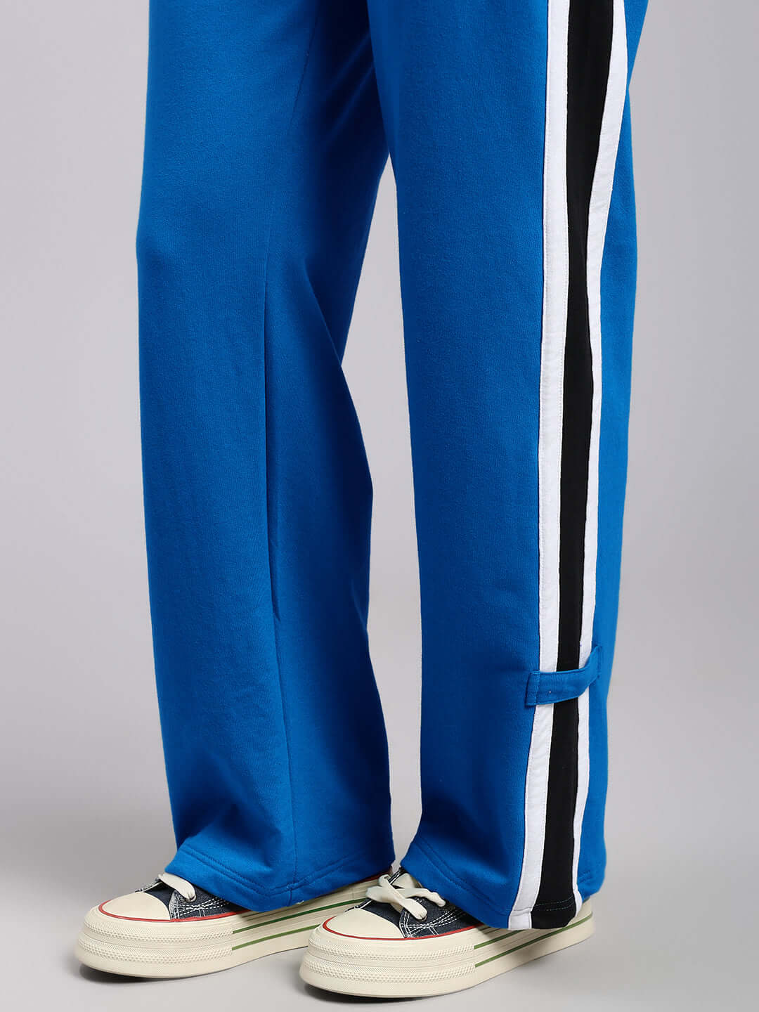 Close-up of WOMENS ROSSTON FLAT-OUT RELAXED FIT JOGGERS BLUE with striped detailing on the side, paired with sneakers.