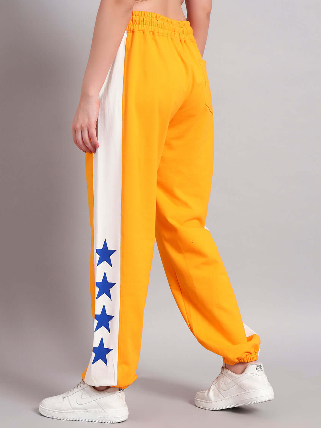 Back view of women's orange-white ROX Primer relaxed fit joggers with blue star detailing, made to order by DUDS.