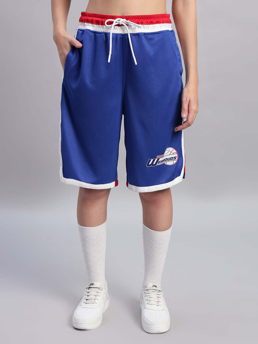Person wearing WOMEN'S PORTIA GYM CO-ORD SET ROYAL BLUE, featuring royal blue athletic shorts and a red waistband for activewear style.