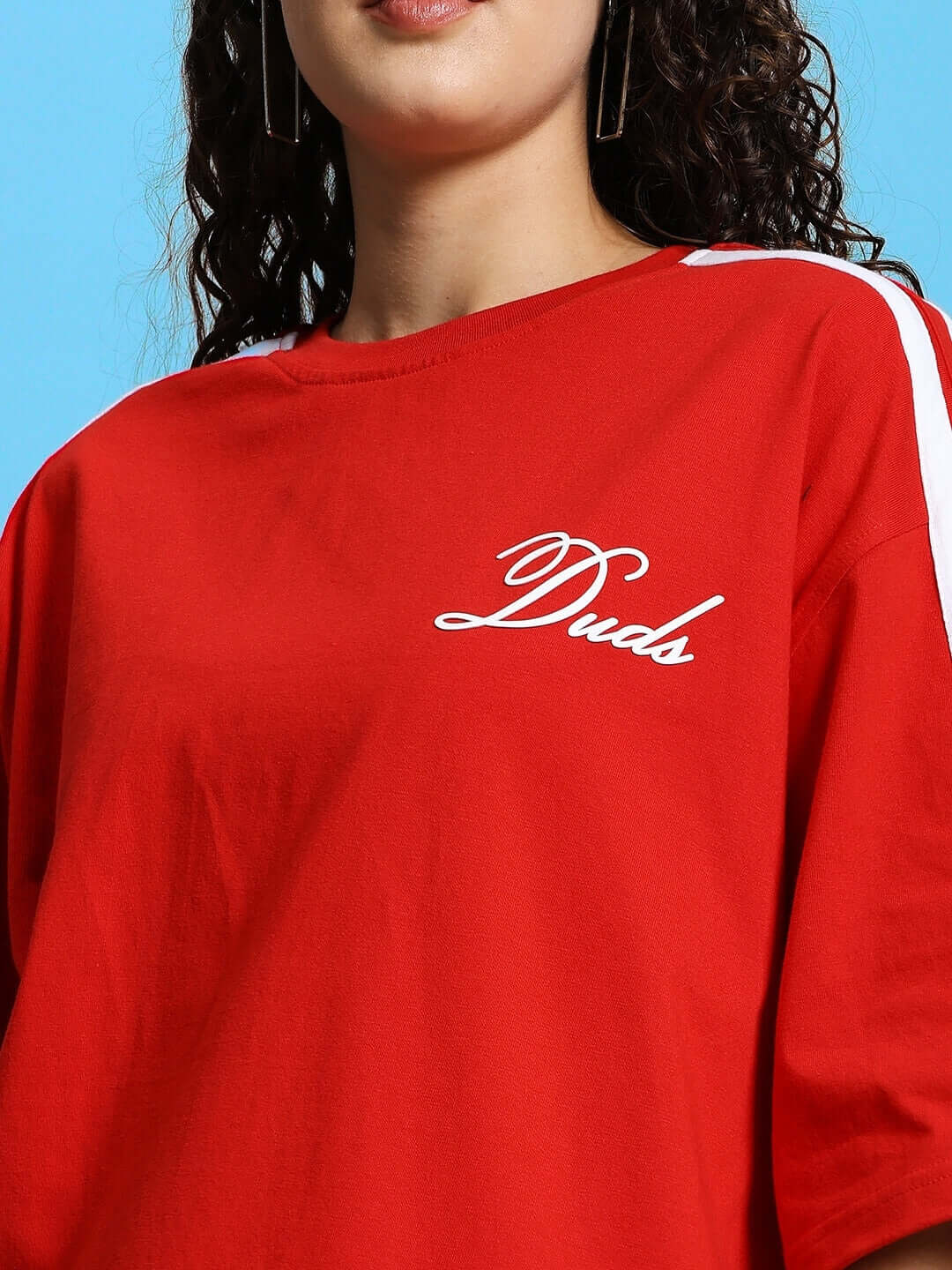 Woman wearing red oversized t-shirt with white 'Duds' logo, featuring premium cotton fabric, from Color By Colours.