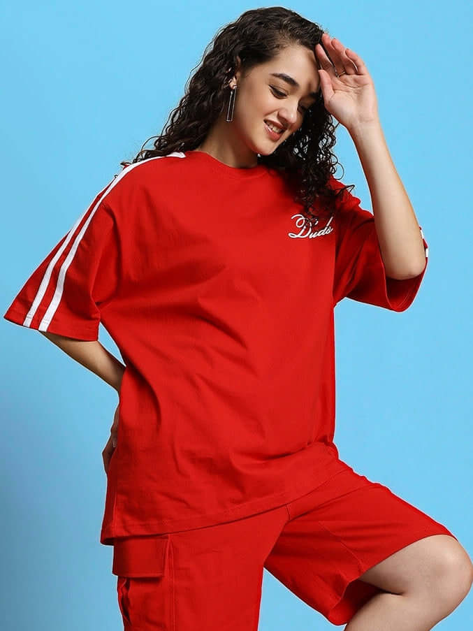 Woman wearing red over-sized Scotia t-shirt made of premium cotton, featuring white stripes on sleeves, against blue background.
