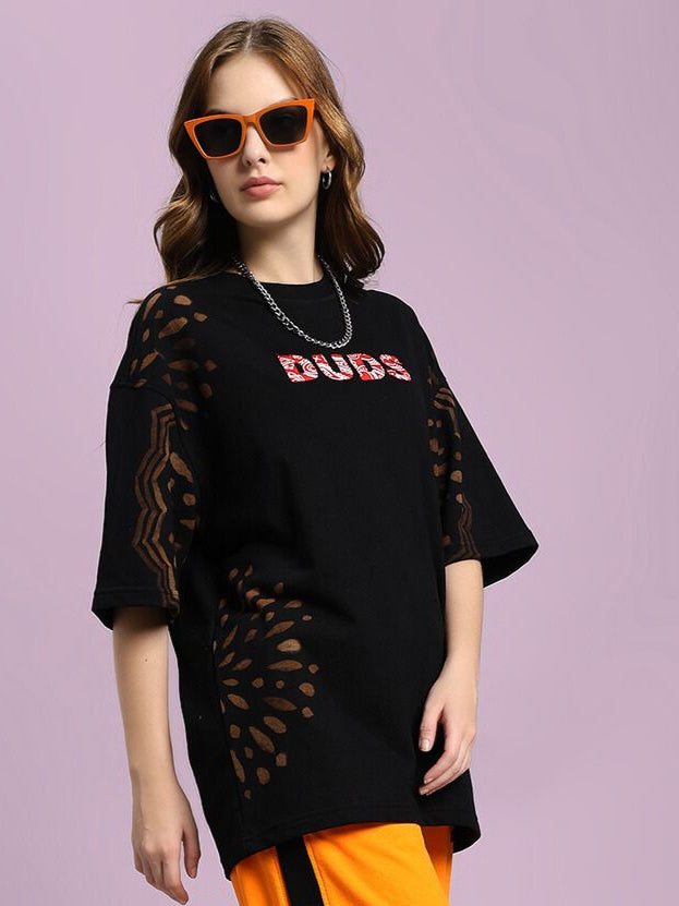 Model wearing WOMEN'S SHADOW SWIRL TIE-DYE T-SHIRT BLACK with subtle tie-dye pattern and orange sunglasses, styled casually.
