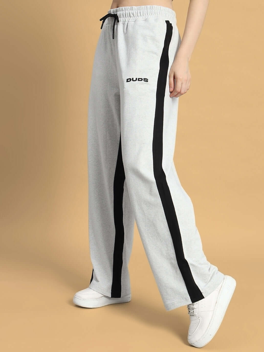 Woman wearing melange grey-black baggy joggers by DUDS, featuring side seams and drawstring waistband.