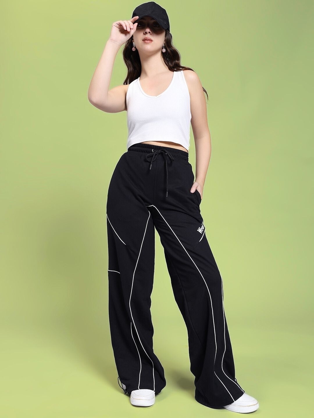 Model wearing WOMEN SIGNATURE PIPING JOGGERS BLACK with contrast piping and relaxed fit, showcasing stylish and comfortable design.