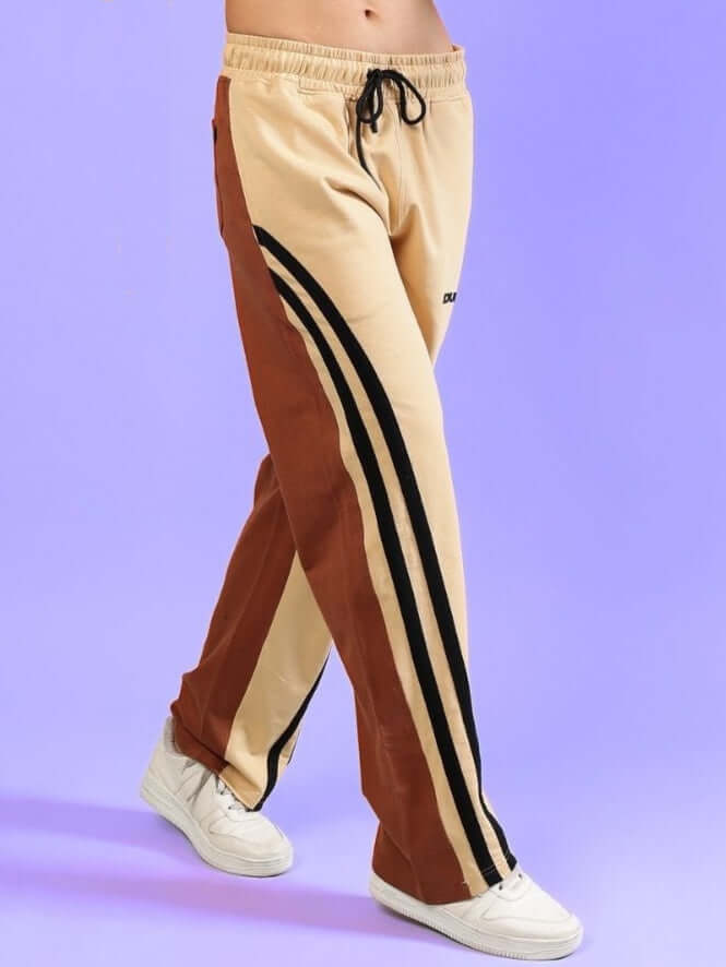 Women's skater Korean baggy joggers in cream brown with black stripes, styled with white sneakers on a purple background.