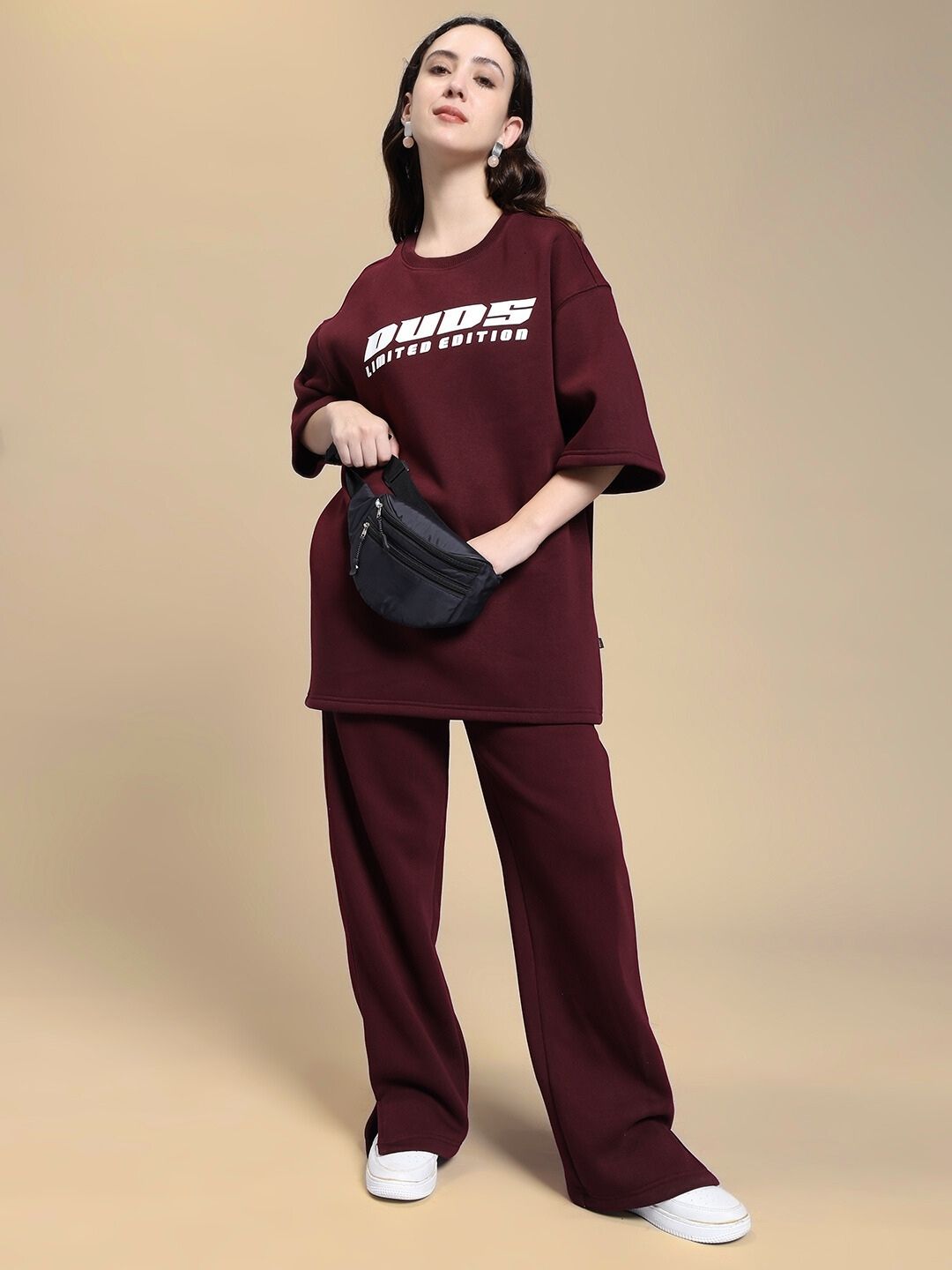 Woman wearing a maroon WOMEN'S SKODA COTTON FLEECE JOGGER MAROON with matching oversized top and a black waist bag.