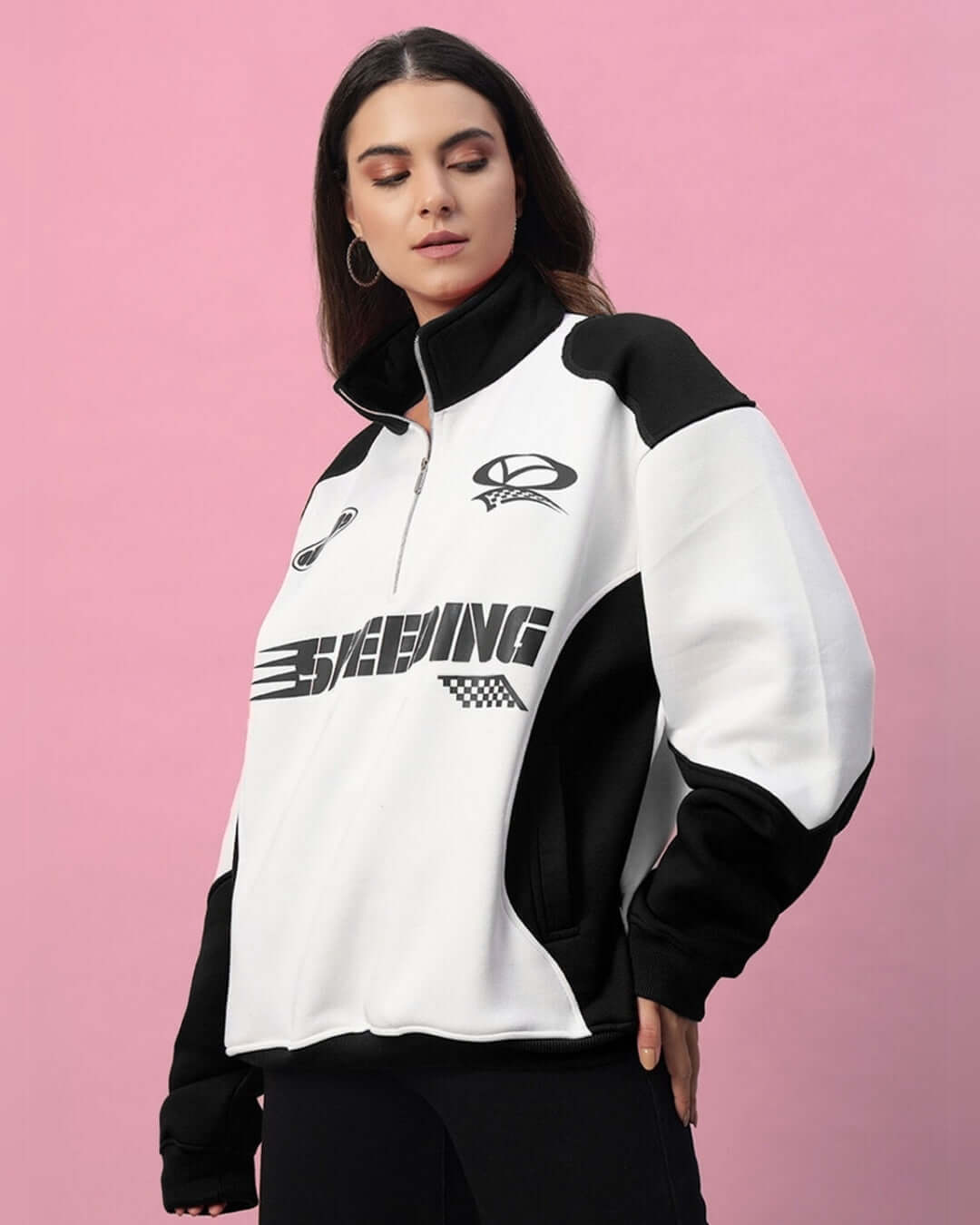 Woman wearing a black and white colorblock jacket featuring bold design elements on a pink background.