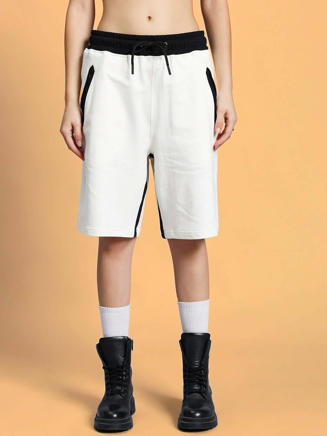Model wearing WOMEN SPLINTER SUMMER CO-ORD SET OFF WHITE, showcasing stylish off-white shorts paired with black boots.