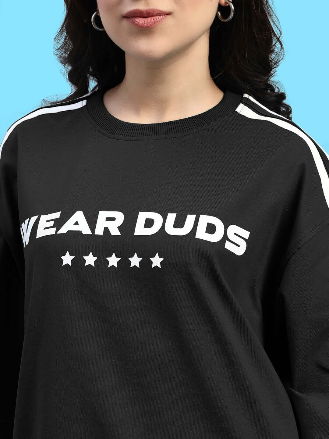 Close-up of Womens Star Jumper Summer Co-Ord Set Black top with design details on a model against a blue background.