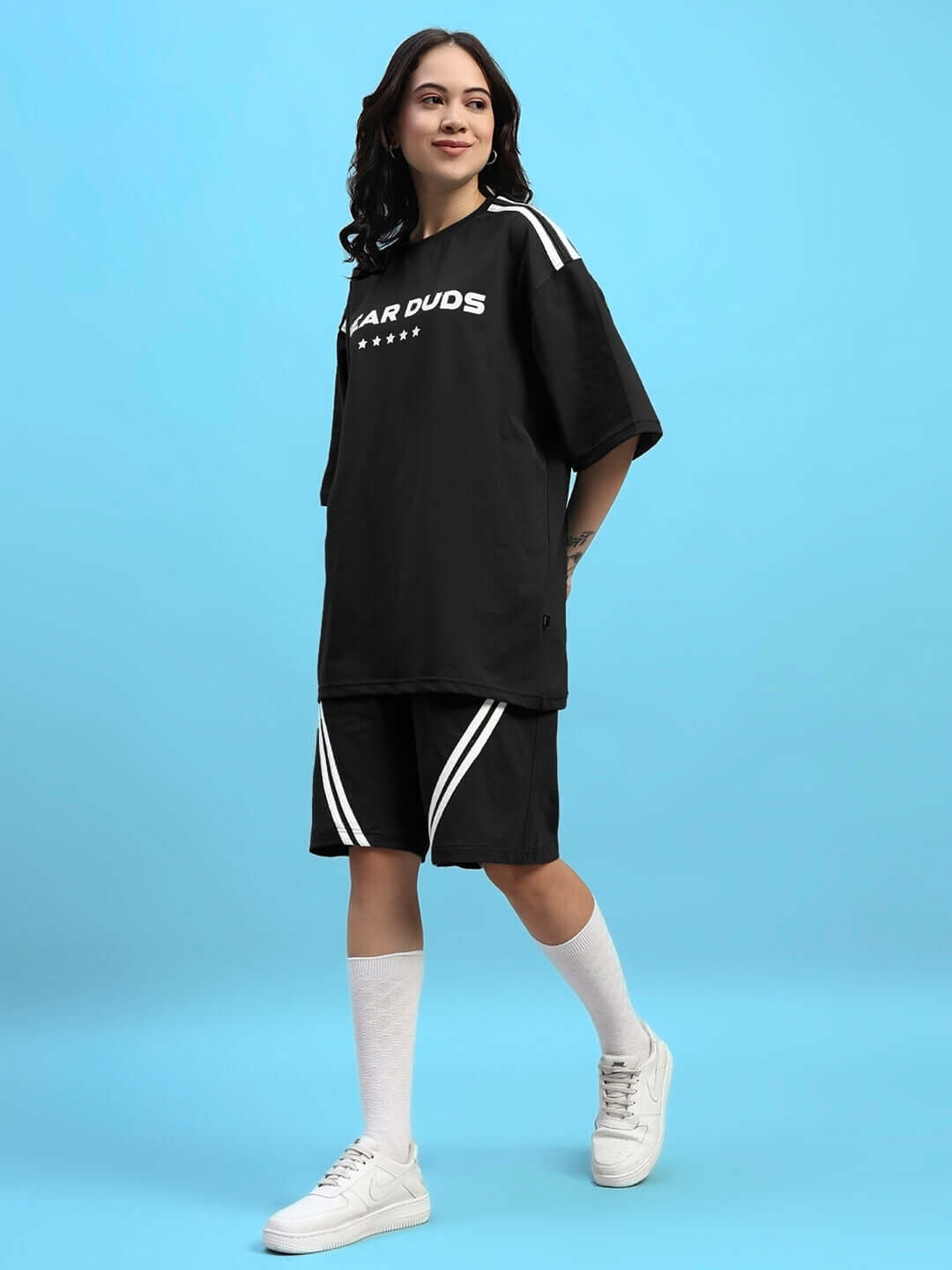 Woman wearing Womens Star Jumper Summer Co-Ord Set Black with sneakers, showcasing stylish streetwear fashion.