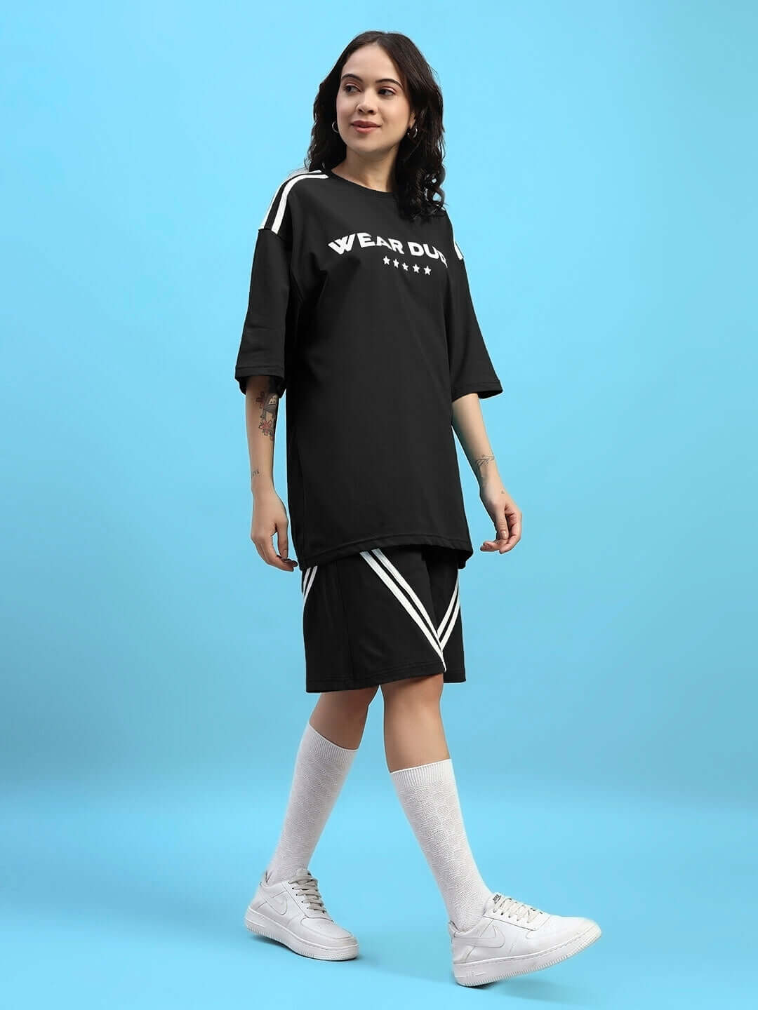 Model wearing Womens Star Jumper Summer Co-Ord Set Black, featuring oversized black jumper and matching shorts for stylish summer look.