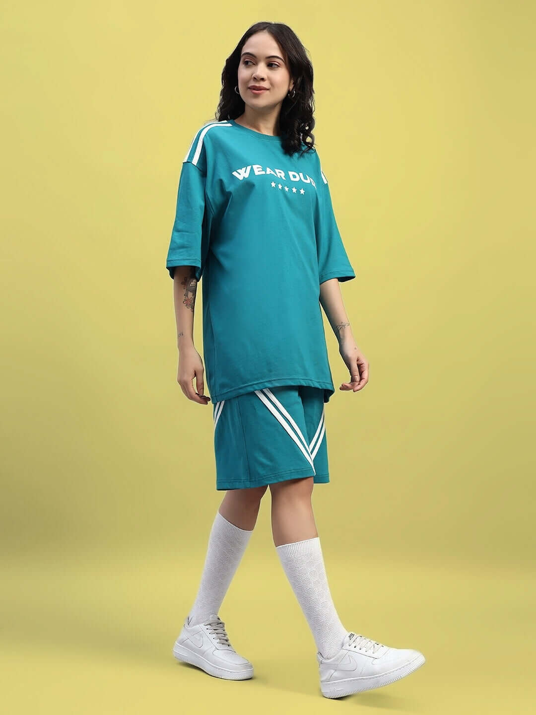 Model wearing WOMEN'S STAR JUMPER OVER-SIZED T-SHIRT TEAL, featuring an oversized fit and bold color, perfect for streetwear fashion.
