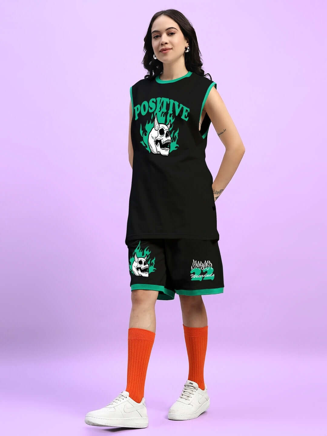 Model wearing Women's Stay Positive Co-Ord Set in black with graphic design, premium cotton fabric, and orange socks.