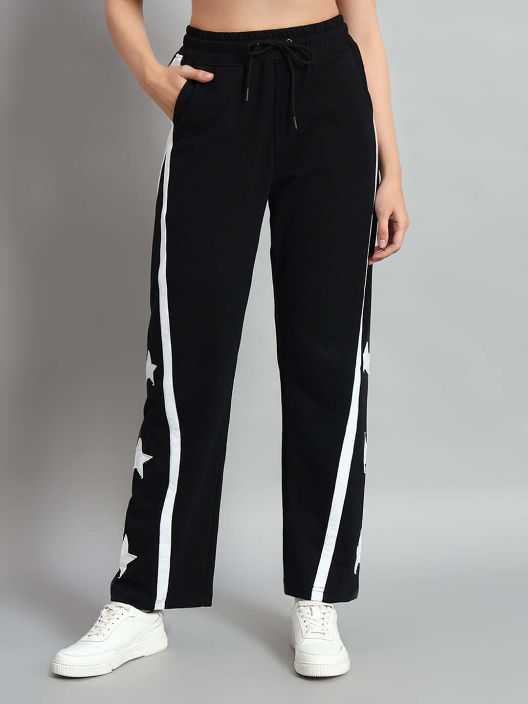 Woman wearing black women's stellar relaxed joggers with star design, paired with white sneakers.