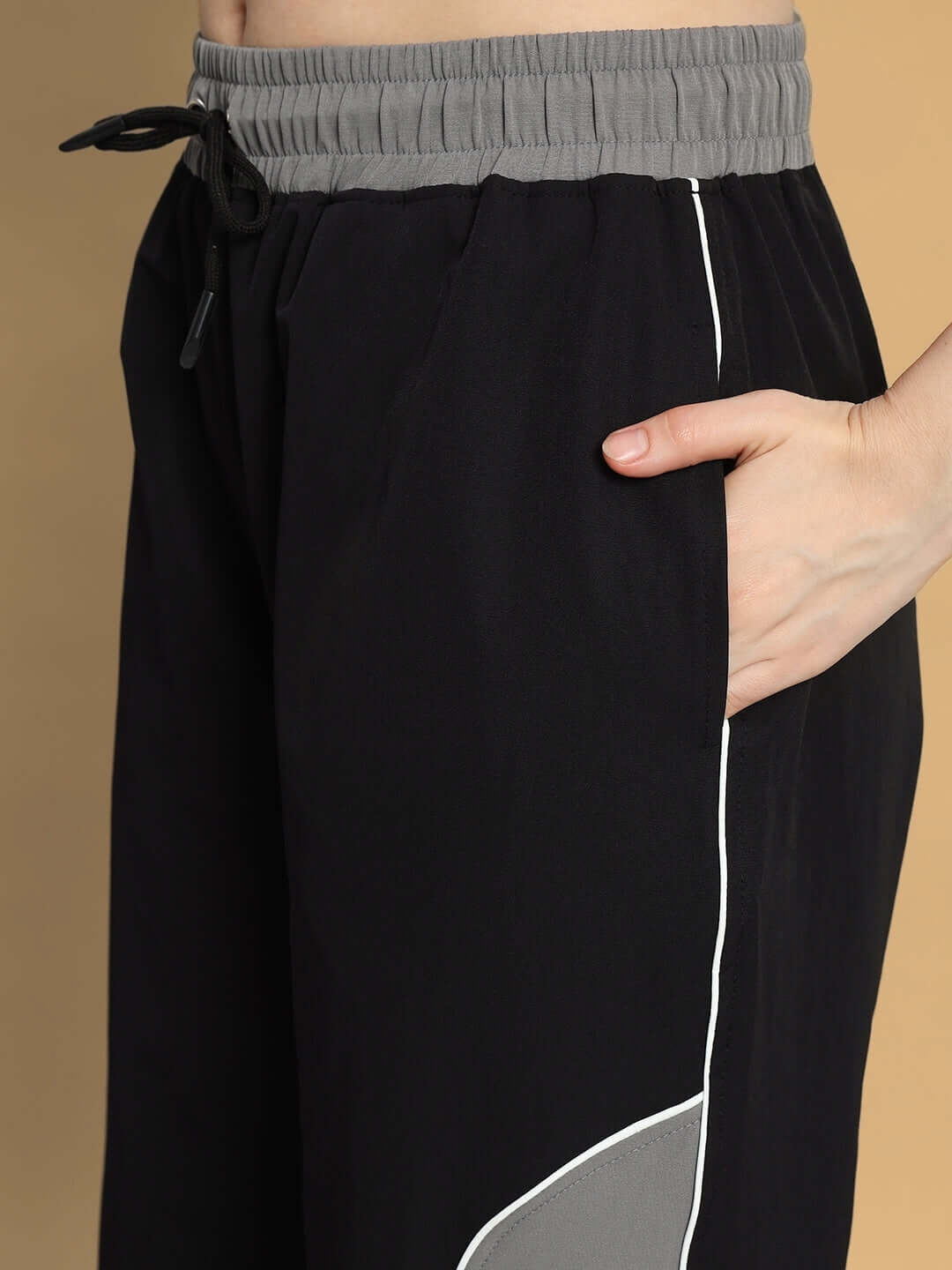 Close-up of black-grey women's relaxed fit cargo pants with elastic waistband and side pocket detail.