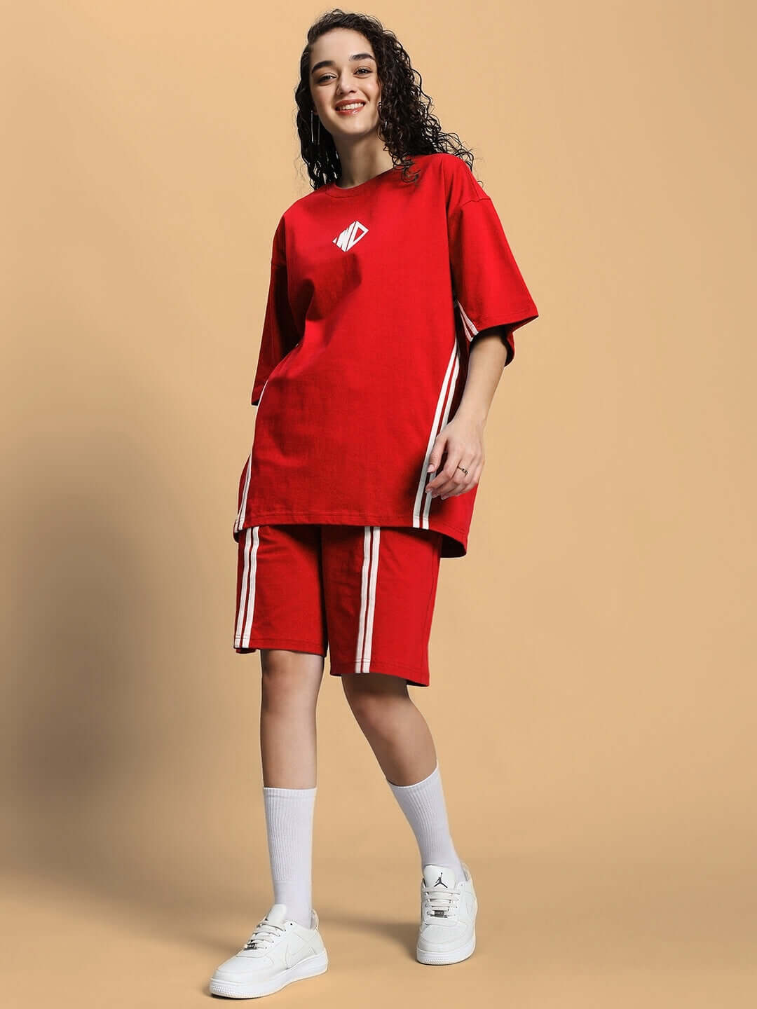 Woman wearing WOMEN'S OUTLOOK SUMMER CO-ORD SHORTS SET RED, featuring a vibrant red t-shirt and shorts, styled with white sneakers.