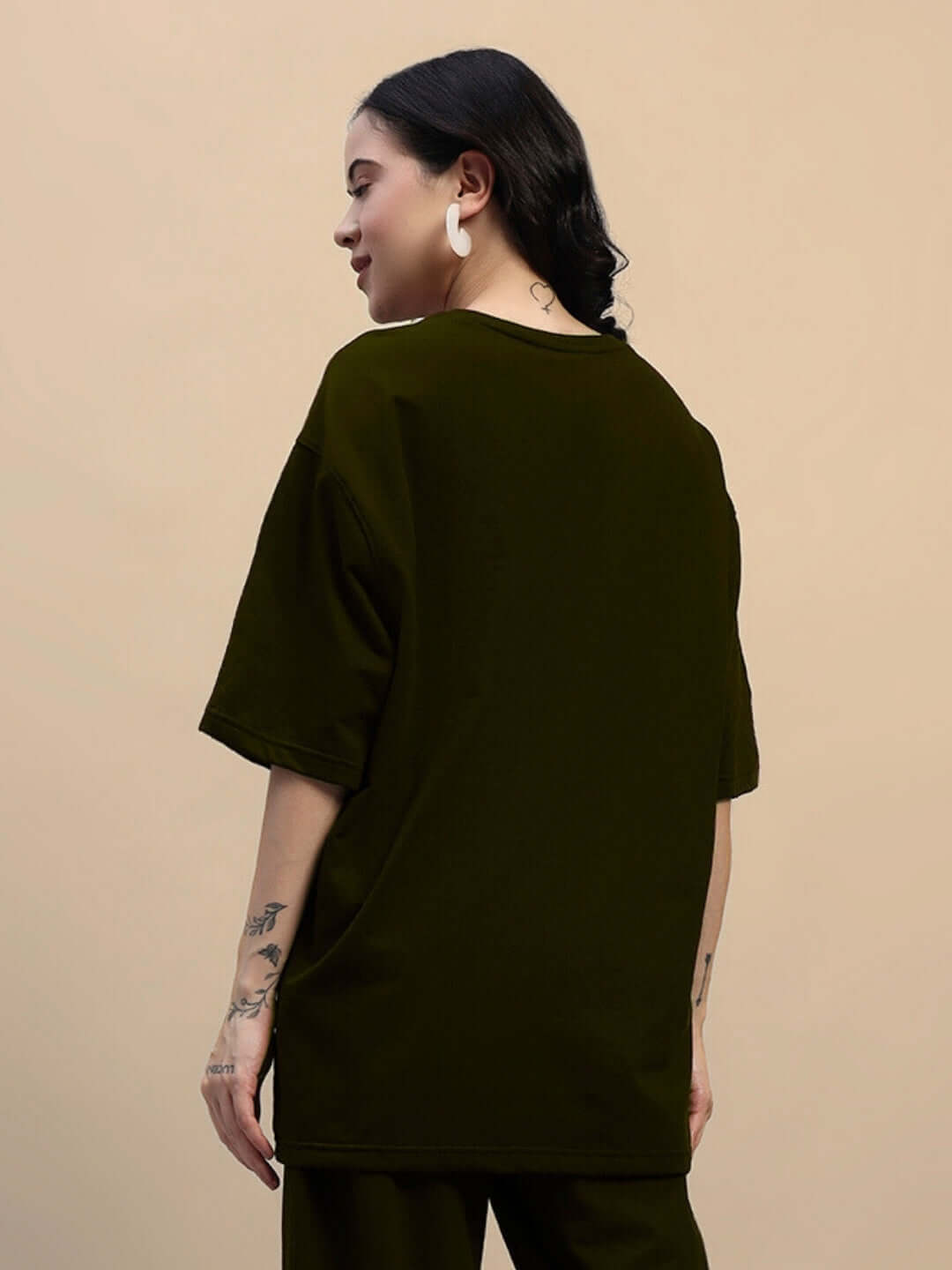 Woman wearing an olive green oversized T-shirt made from premium cotton fabric, featuring a relaxed fit and stylish design.