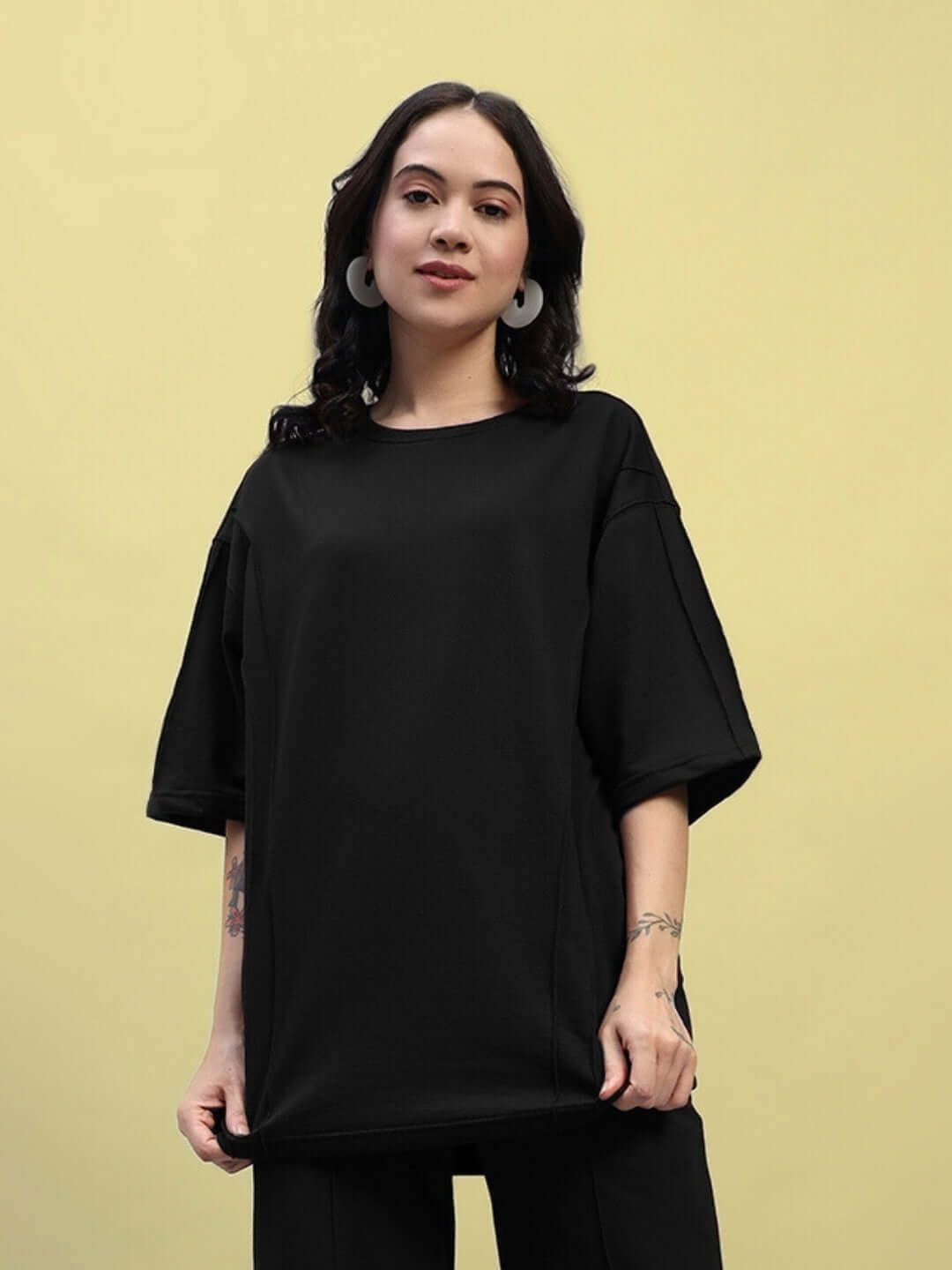 Woman wearing a black oversized T-shirt, made from premium heavy gauge fabric, ideal for casual wear and featuring comfortable fit.
