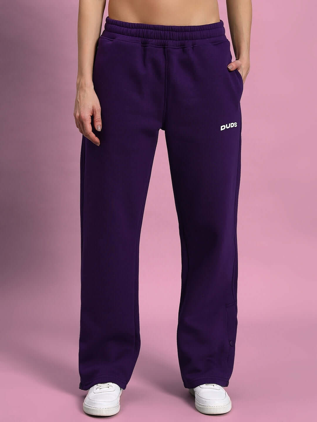 Woman wearing WOMEN SOOTY FLEECE CARGO PANT PURPLE standing against pink background.