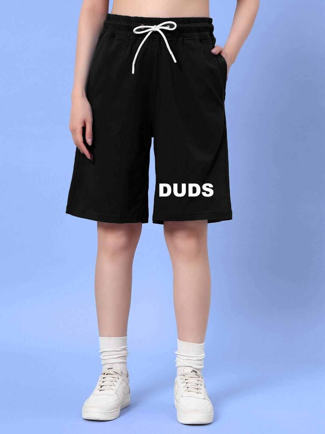 Alt Tag: Woman wearing DUDS black summer shorts with a drawstring waist and white lettering, showcasing casual comfort and customizable fit options.