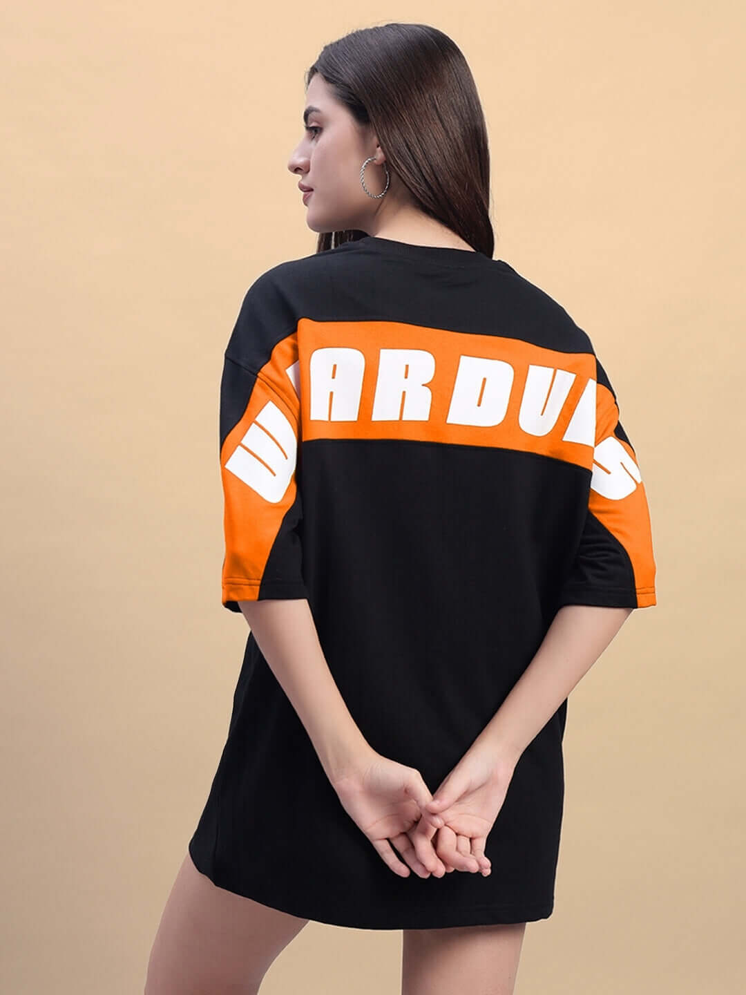 Woman wearing oversized black and orange t-shirt with text on back, made from premium cotton and elastane blend, by Color By Colours.