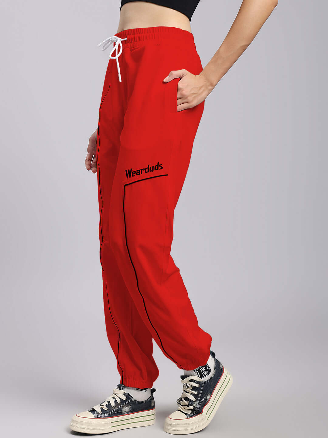 Women's red relaxed fit joggers by DUDS, featuring custom fit option and graphic logo, modeled with casual sneakers.