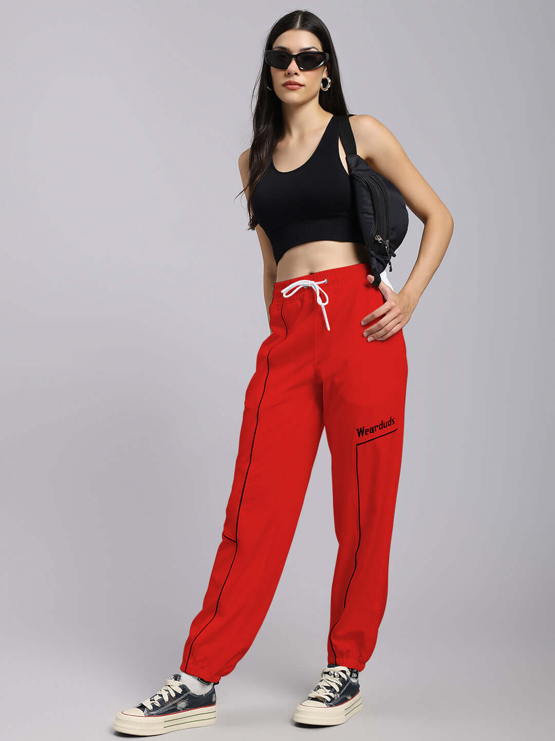 Woman wearing WOMENS TOKYO RELAXED FIT JOGGERS RED with black top and sunglasses, showcasing casual and vibrant street style.