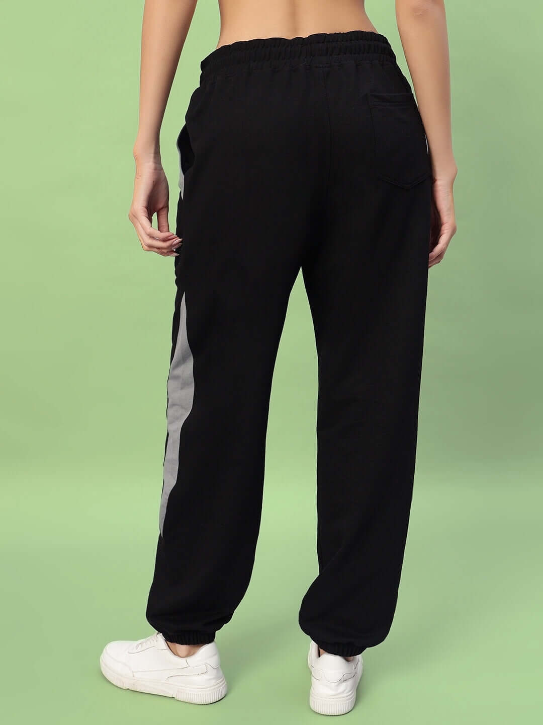 Back view of Women's Trackpoint Baggy Joggers in black-grey, featuring a relaxed fit and elastic waistband, styled with white sneakers.