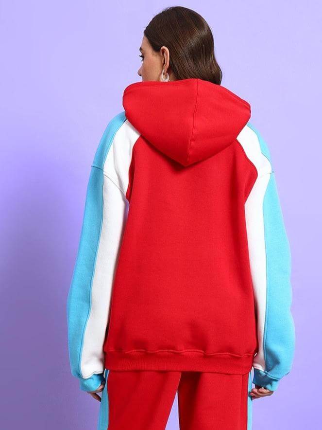 Back view of women's red colorblock co-ord with a hood and blue sleeves, shown against a purple background.