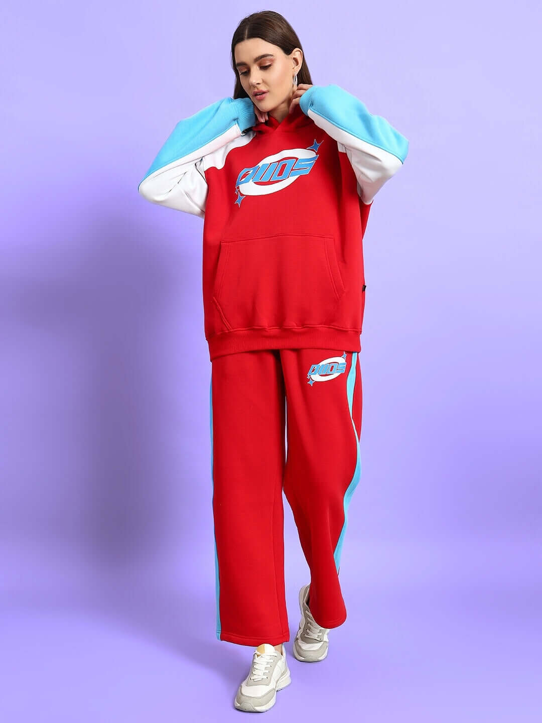 Woman wearing a red colorblock co-ord set with blue details, featuring a hoodie and pants.