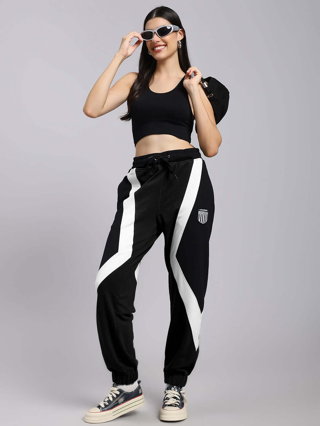 Woman wearing DUDS ULTRA Colorblock Relaxed-Fit Joggers in black and white with sunglasses and sneakers.