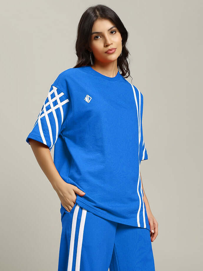 Woman wearing blue oversized t-shirt with white stripes, crafted from premium cotton blend fabric, showcasing relaxed fit fashion.