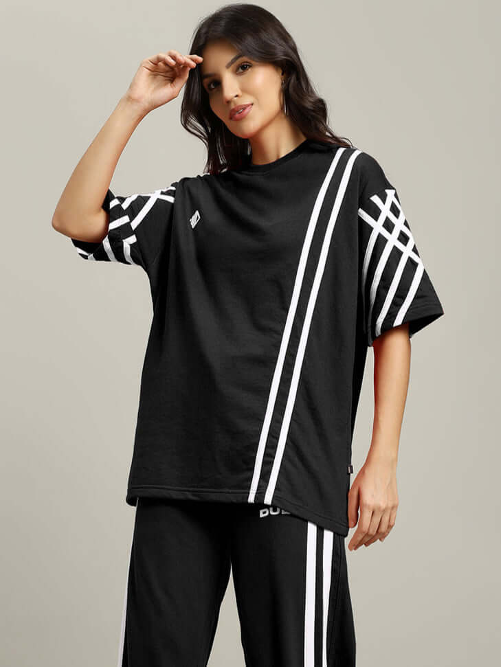 Woman wearing oversized black t-shirt with white stripes, made of premium cotton blend, 240 GSM, suitable for casual wear. Made in India.