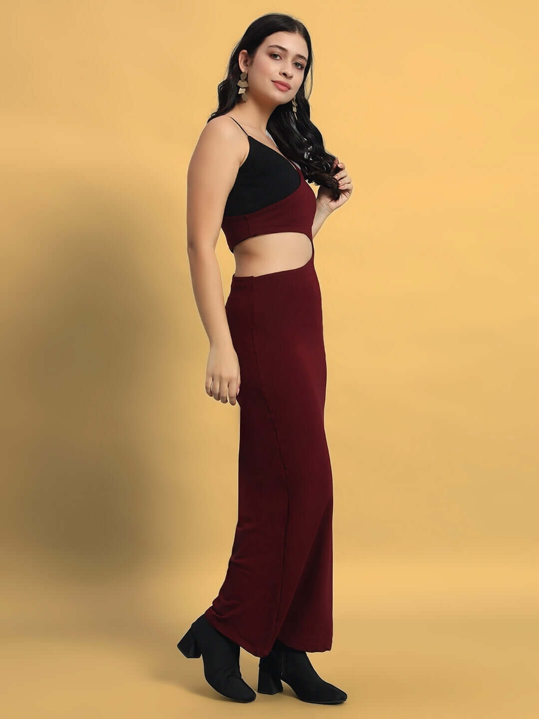Woman wearing maroon Valencia Lycra dress with black top detail, elegantly styled with black ankle boots against a neutral backdrop.
