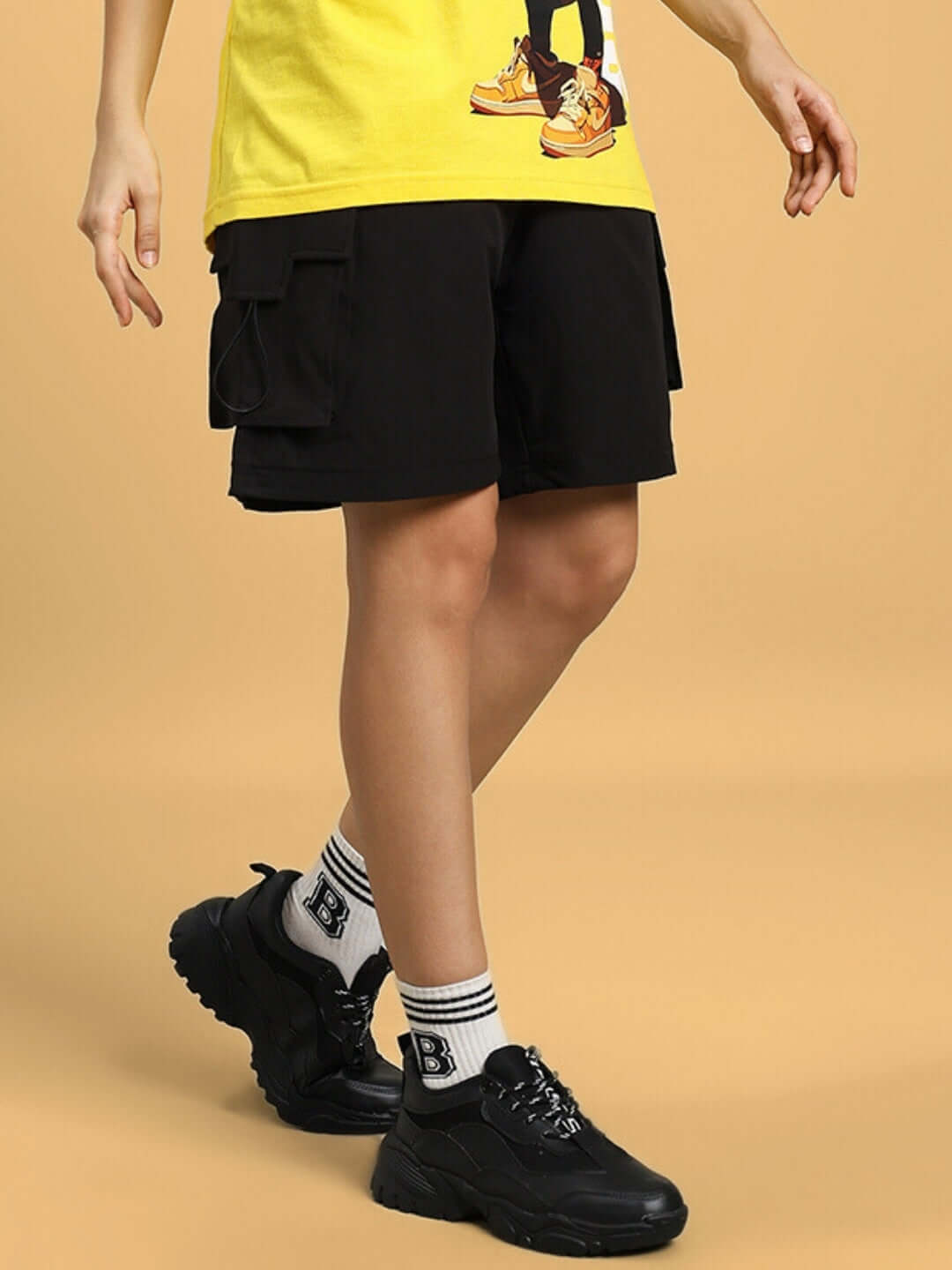 Woman wearing black Vega cargo shorts paired with a yellow t-shirt and black sneakers, highlighting a casual and trendy look.