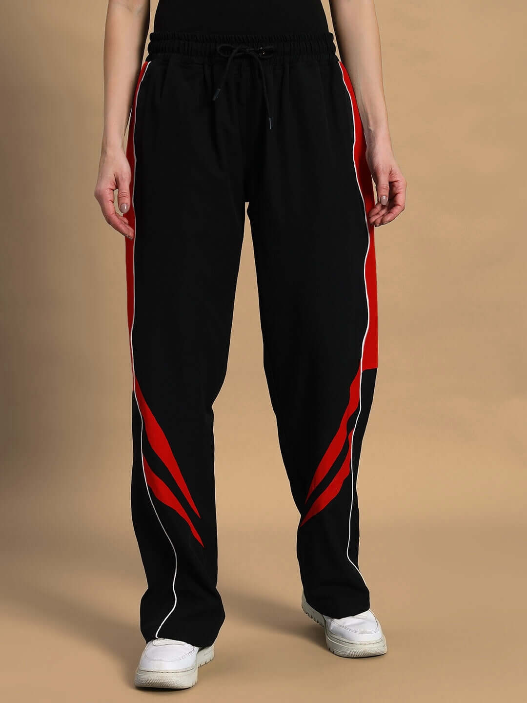 Woman wearing black and red versatile parachute cargo pants with custom fit option, available for prepaid orders, on beige background.