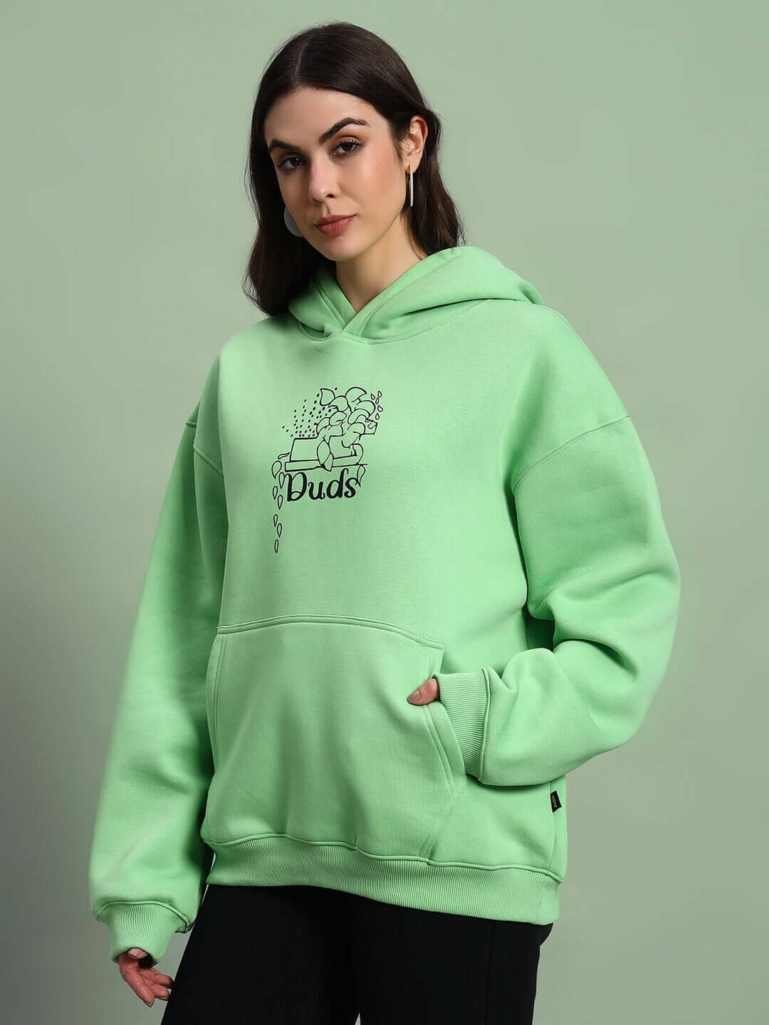 Woman wearing WOMEN VOODO FLEECE OVERSIZED HOODIE GREEN, showcasing vibrant color and stylish streetwear design.