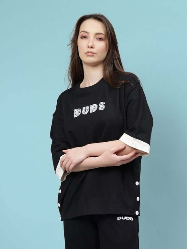 Model wearing Women's Wesent Oversized Black T-Shirt, featuring premium cotton fleece, bio-washed for a soft feel, against blue background.